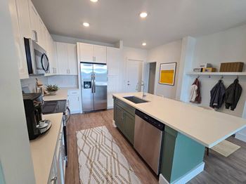 A kitchen with a white counter top and a rug on the floor.
